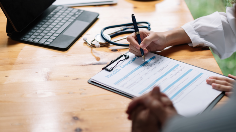 Doctor writing health insurance form on clipboard
